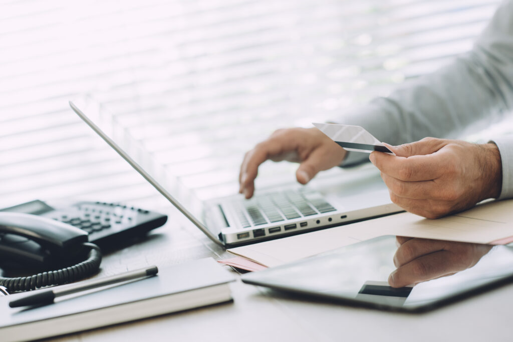 a person holding a card and typing on a laptop